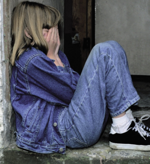 Child sitting with face in hands and crying.